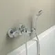 Wandmontierte Badearmatur von Ideal Standard mit verchromter Oberfläche und Handbrause, installiert über einer Badewanne, an heller Wand.